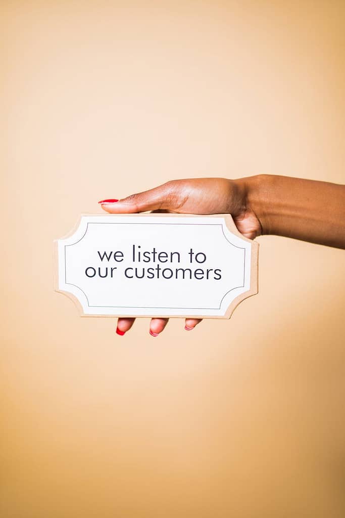 person holding a board with a text saying we listen to our customers
