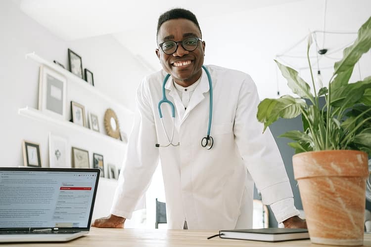 a doctor smiling while leaning on the table - private practice