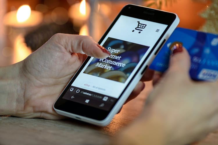 person using black and white smartphone and holding blue card - how to improve your online presence