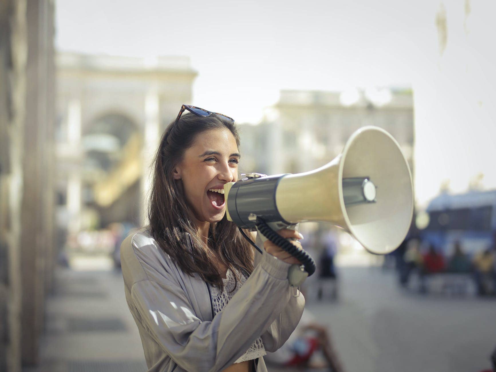 cheerful young woman screaming into megaphone (content distribution strategies)