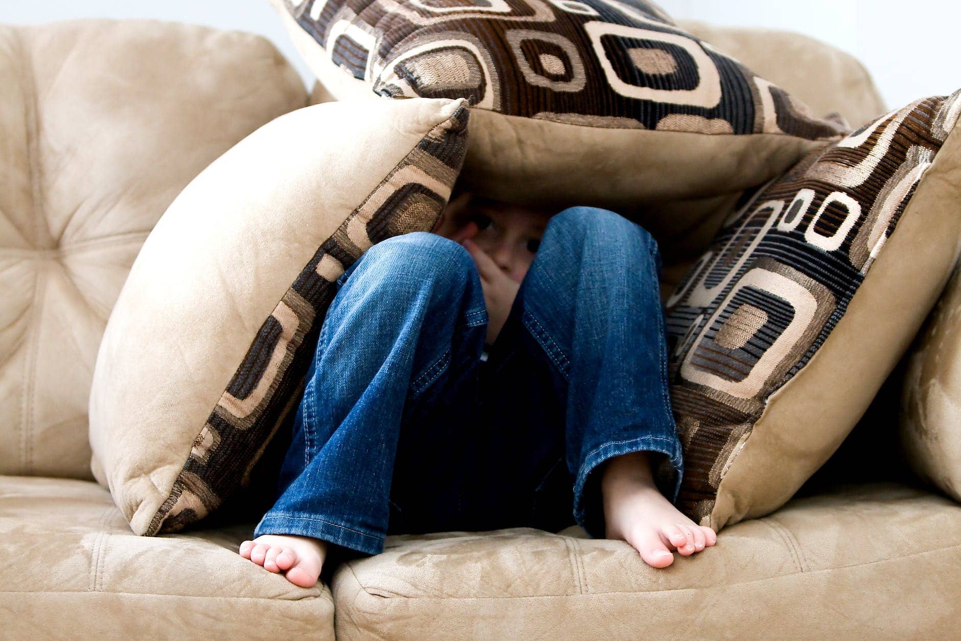 kid hiding on pillows - how to support a child with mental health issues