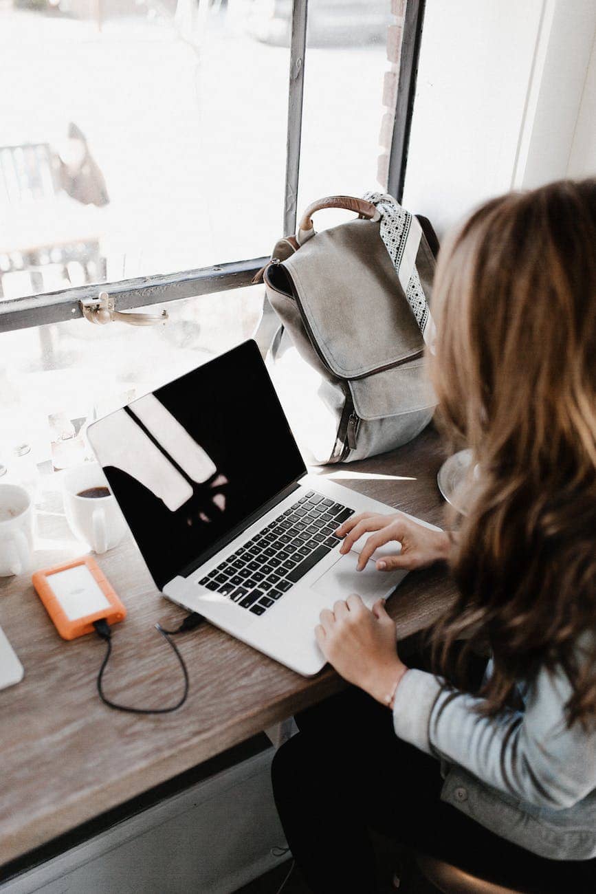 close up photography of woman sitting beside table while using macbook - how to become a copywriter UK. 