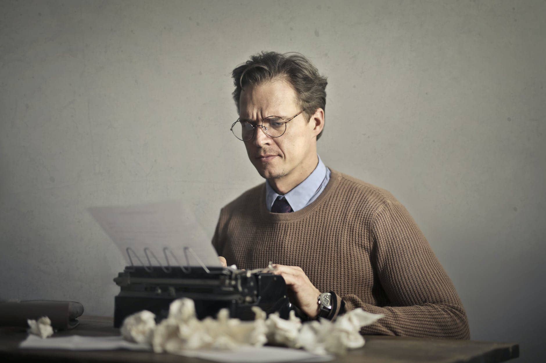 adult frowned male writer working on typewriter at home - plot a novel