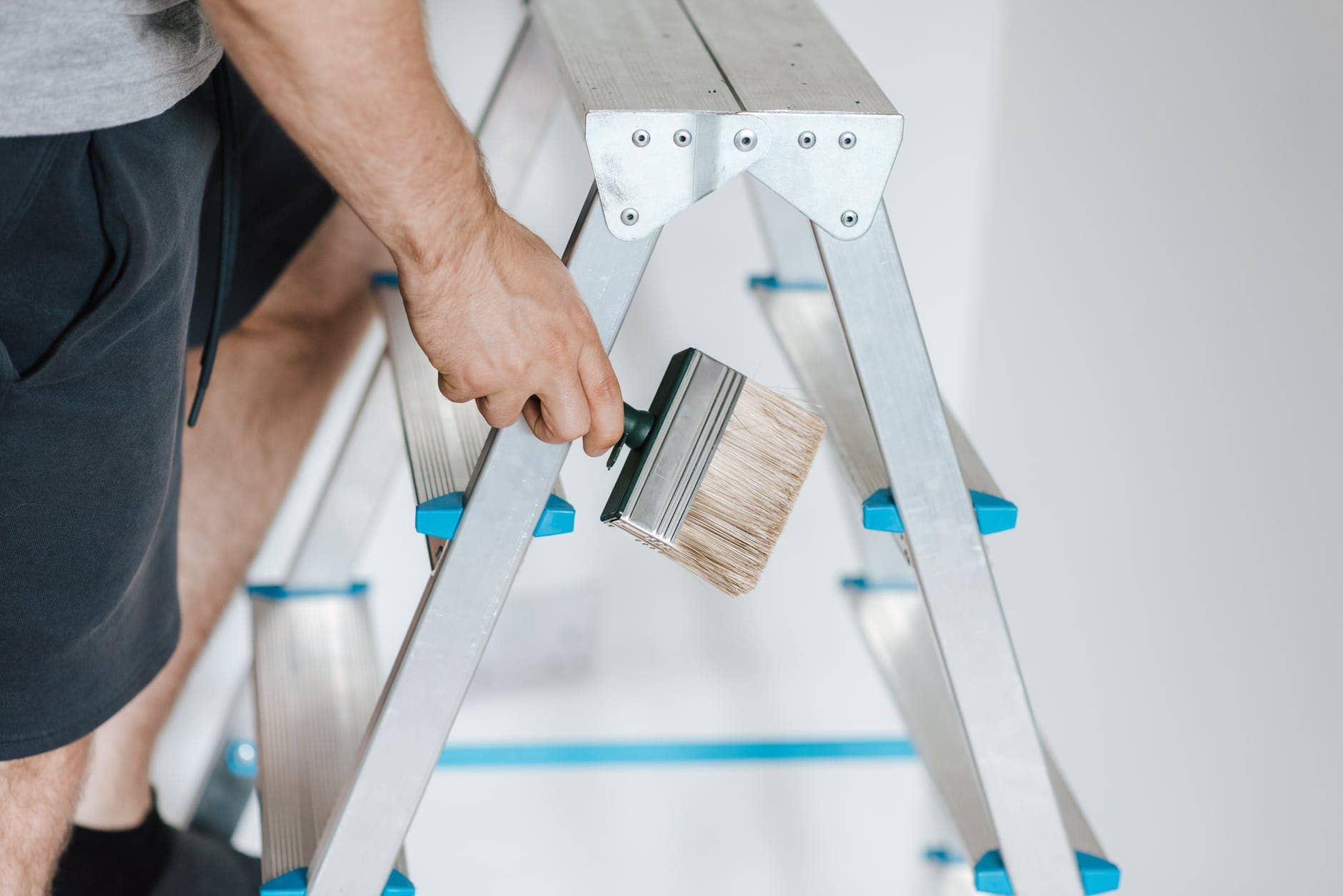 painter with brush climbing ladder during renovation work affordable home improvements