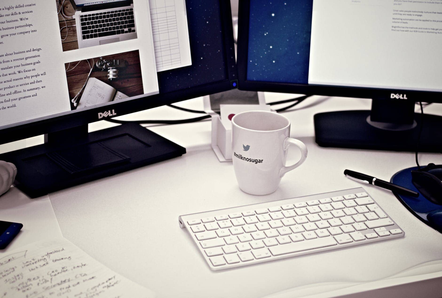 white ceramic mug between apple magic keyboard and two flat screen computer monitors- lifestyle blog post ideas