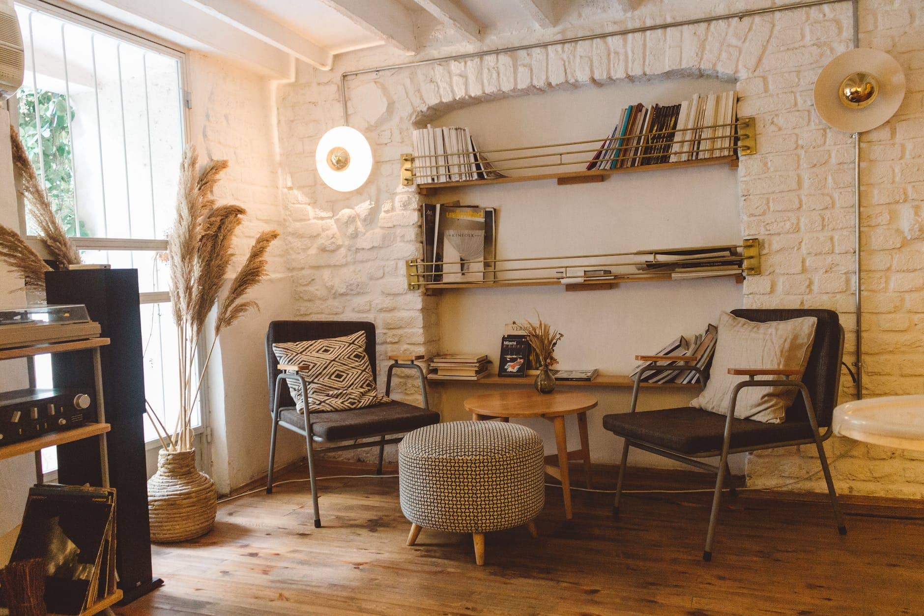 living space with round brown wooden table between two chairs and ottoman chair