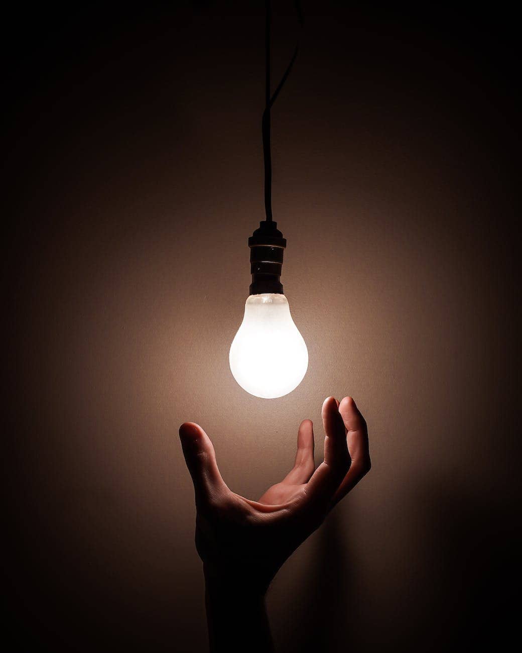 person holding white light bulb - How to save electricity at home