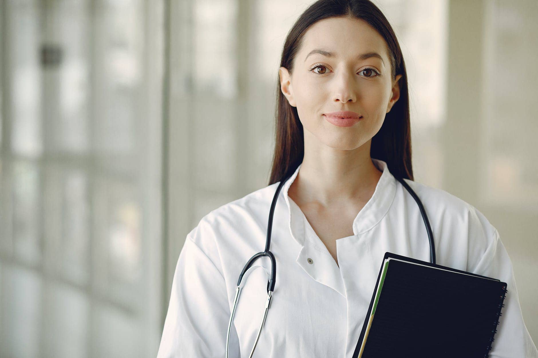young doctor in uniform with stethoscope and notebook in medical room -healthcare productivity