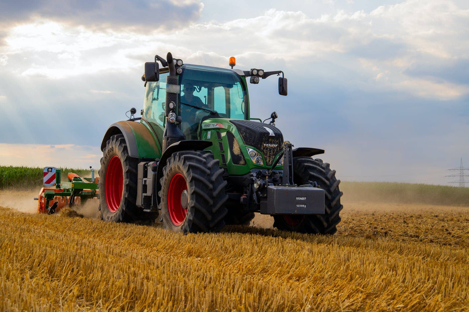 green tractor plowing the fields on focus photography - farming business