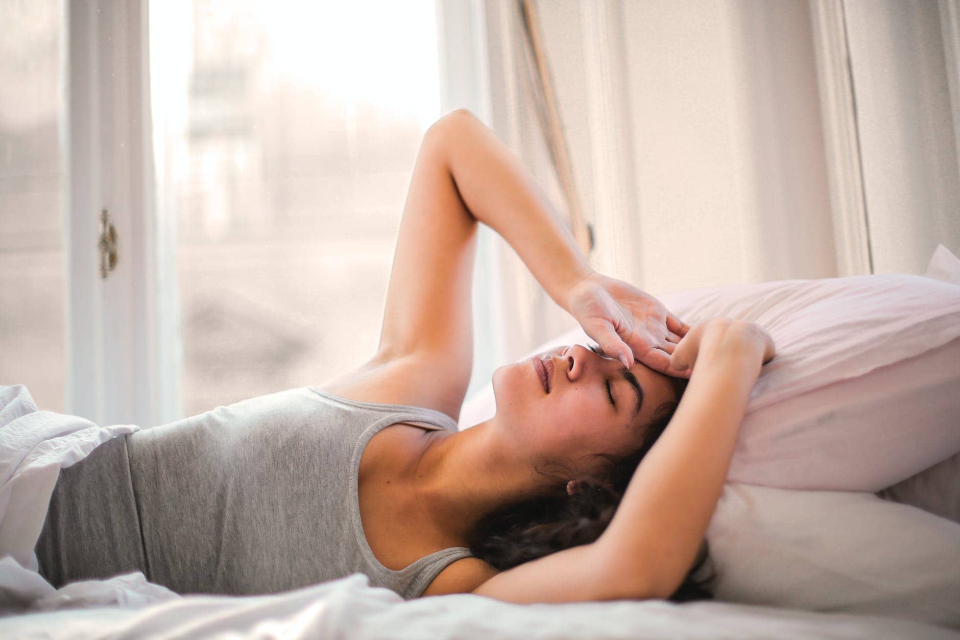woman in gray tank top lying on bed - low-dopamine morning routine