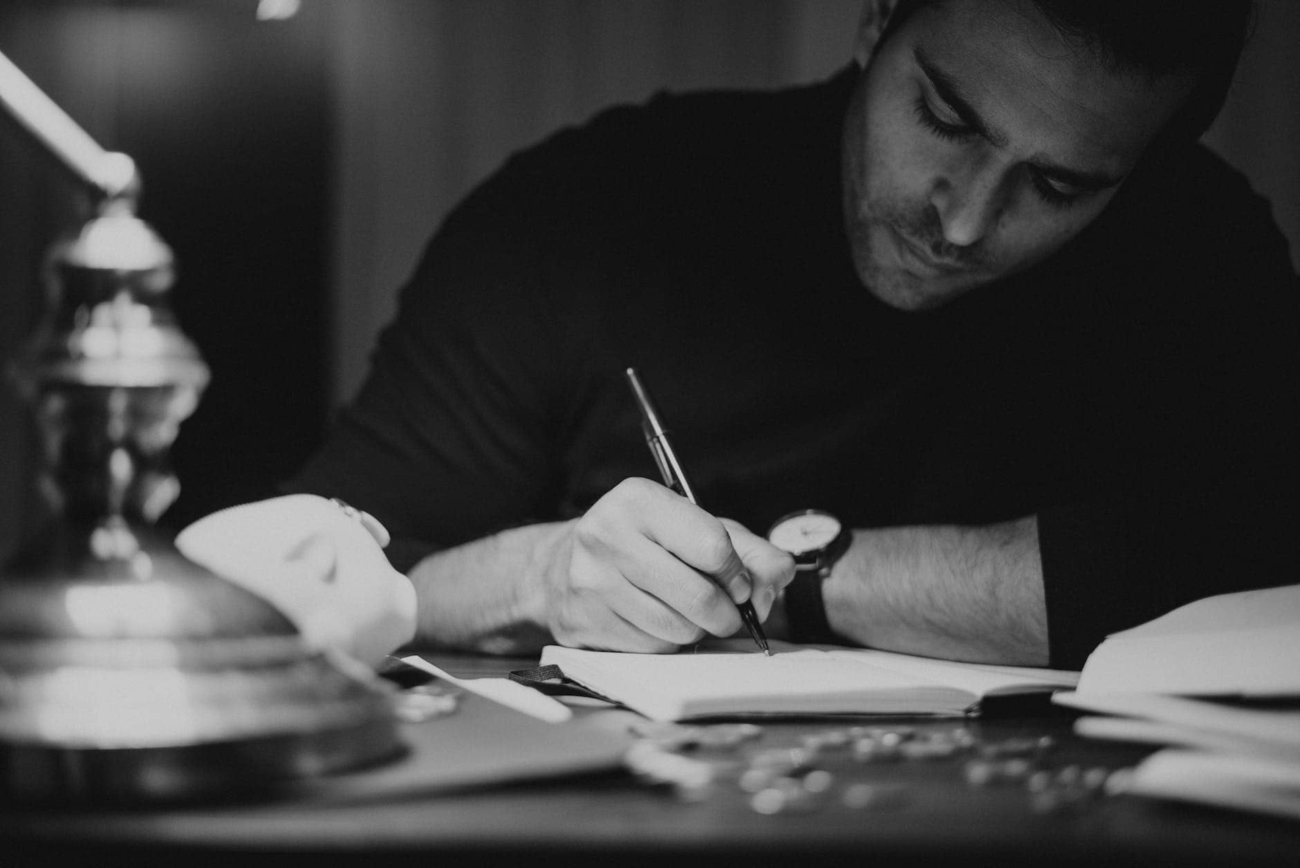 crop man taking notes in copybook in dark home office - how to become a better writer