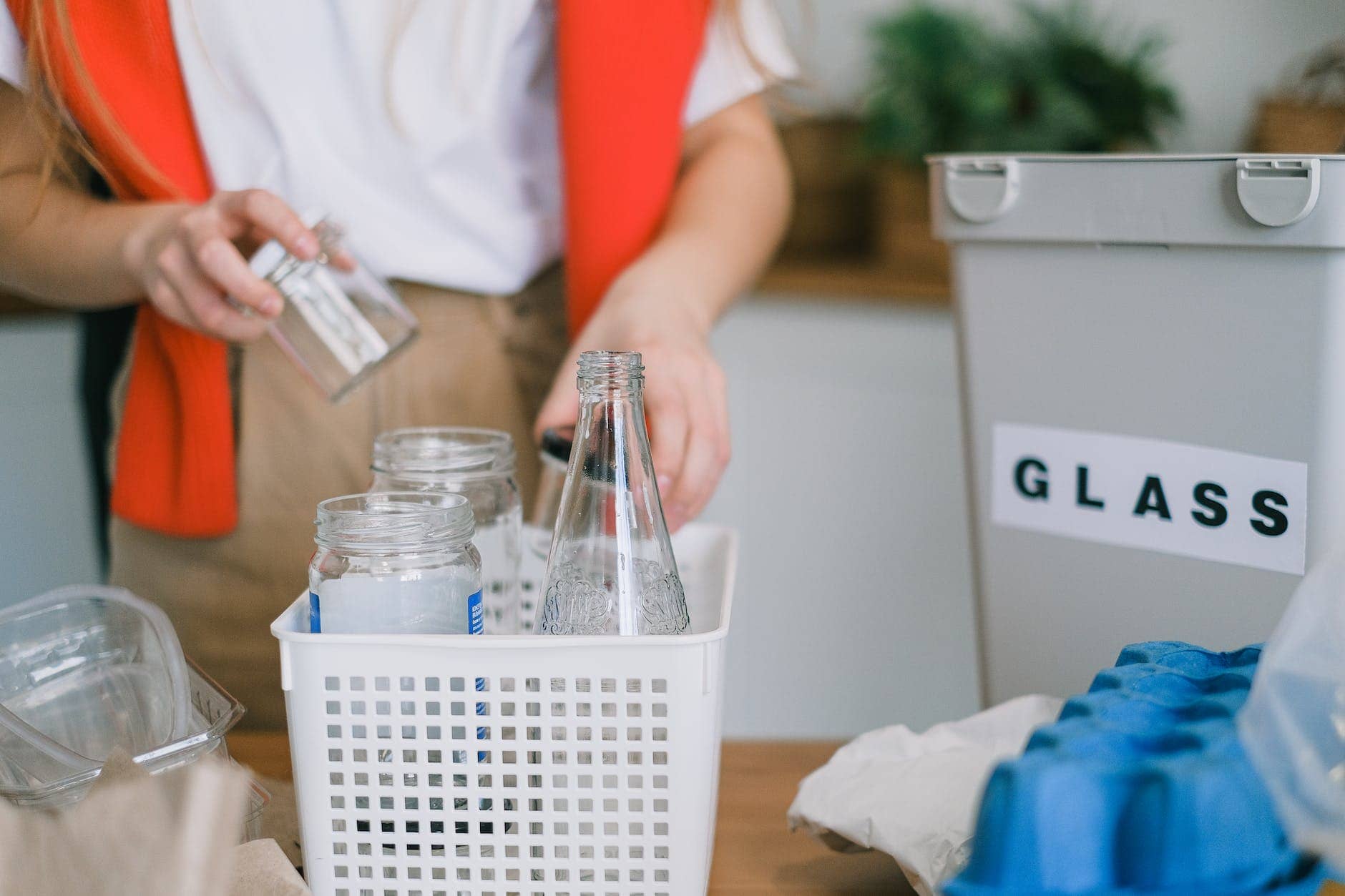 woman selecting glass into plastic container - how to reduce waste in your business