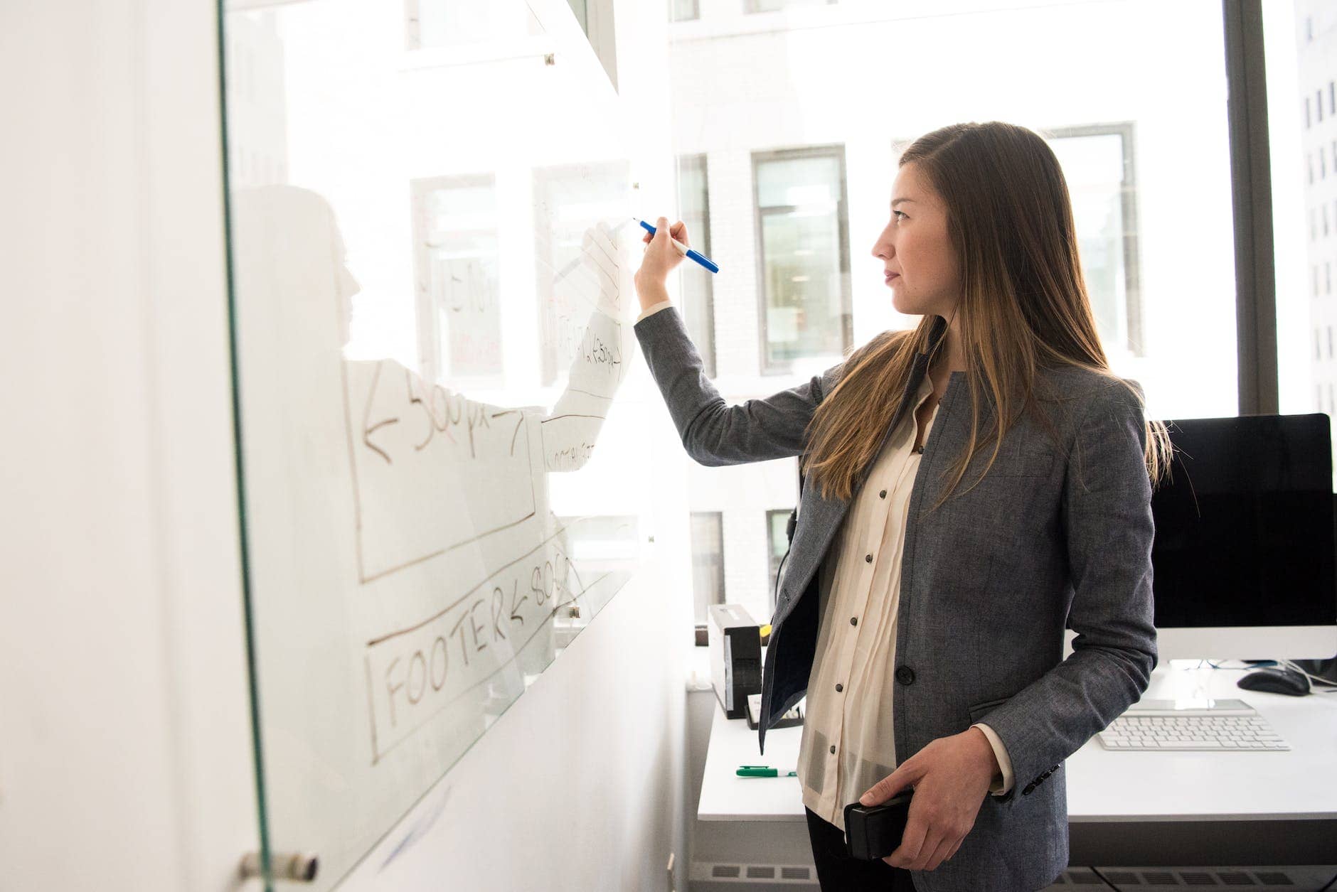 woman wearing gray blazer writing on dry erase board - new business