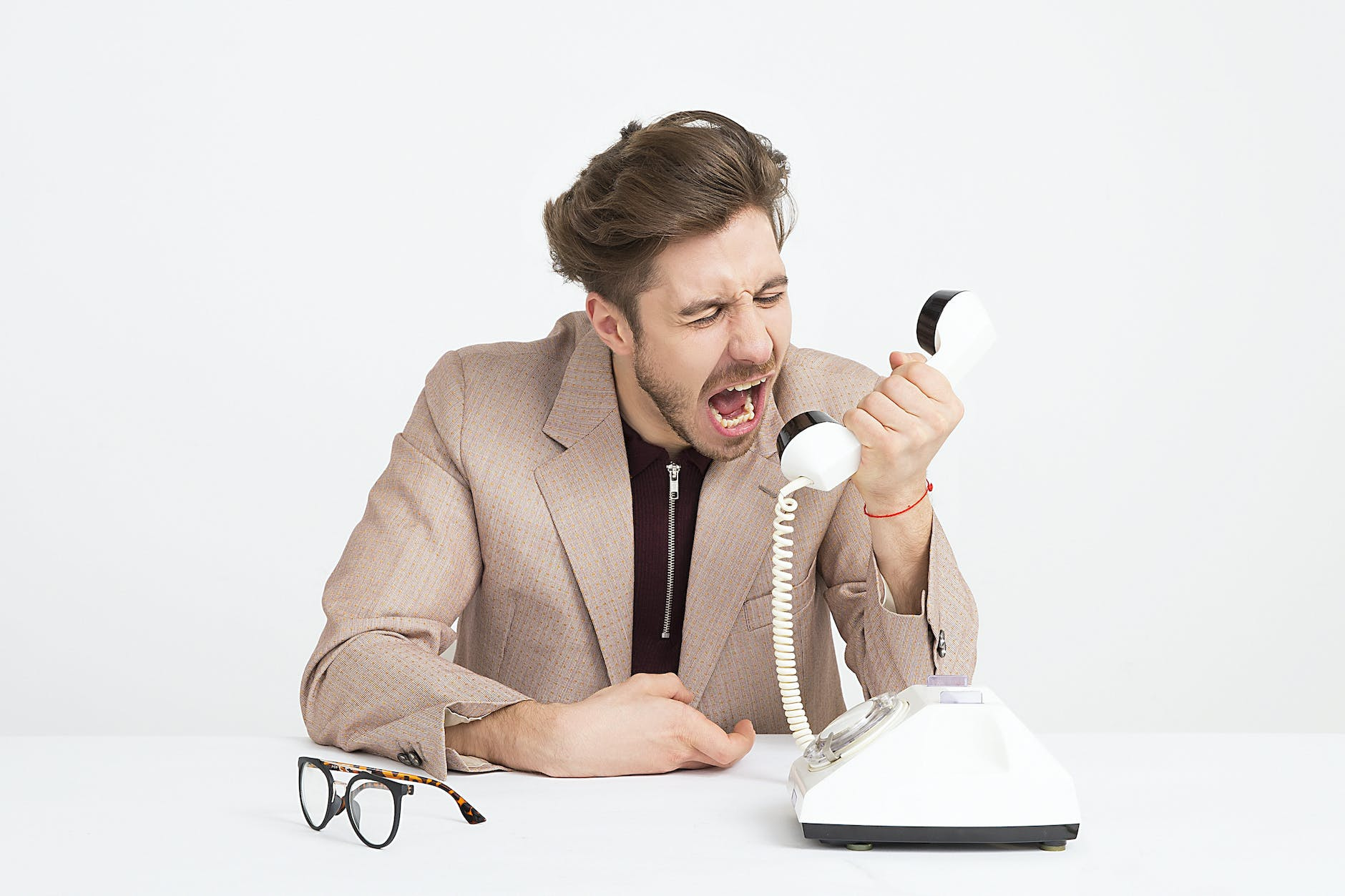 man wearing brown suit jacket mocking on white telephone - Alienating Your Audience