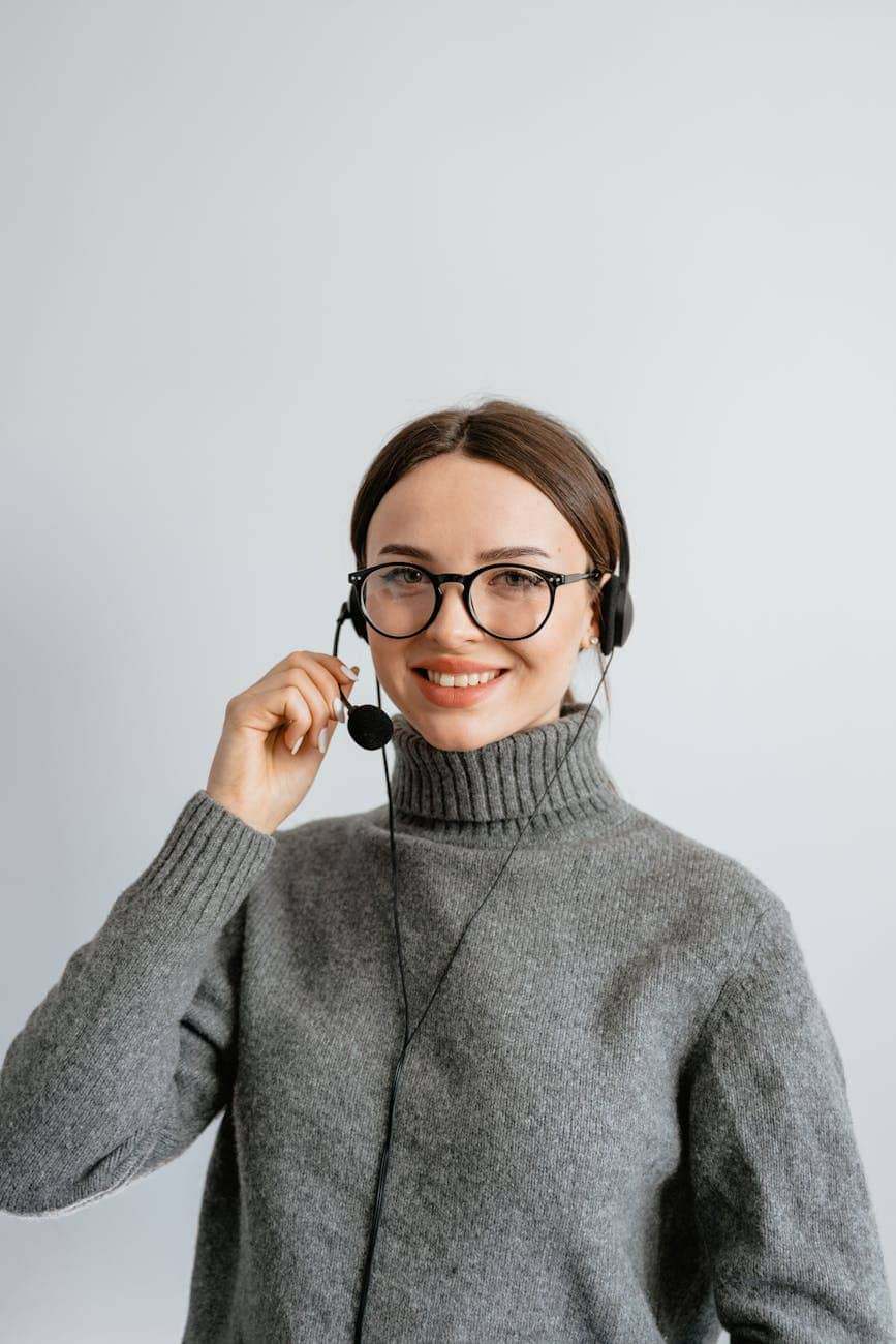 woman in gray turtle neck shirt with black headset and mouthpiece - outsourcing benefits