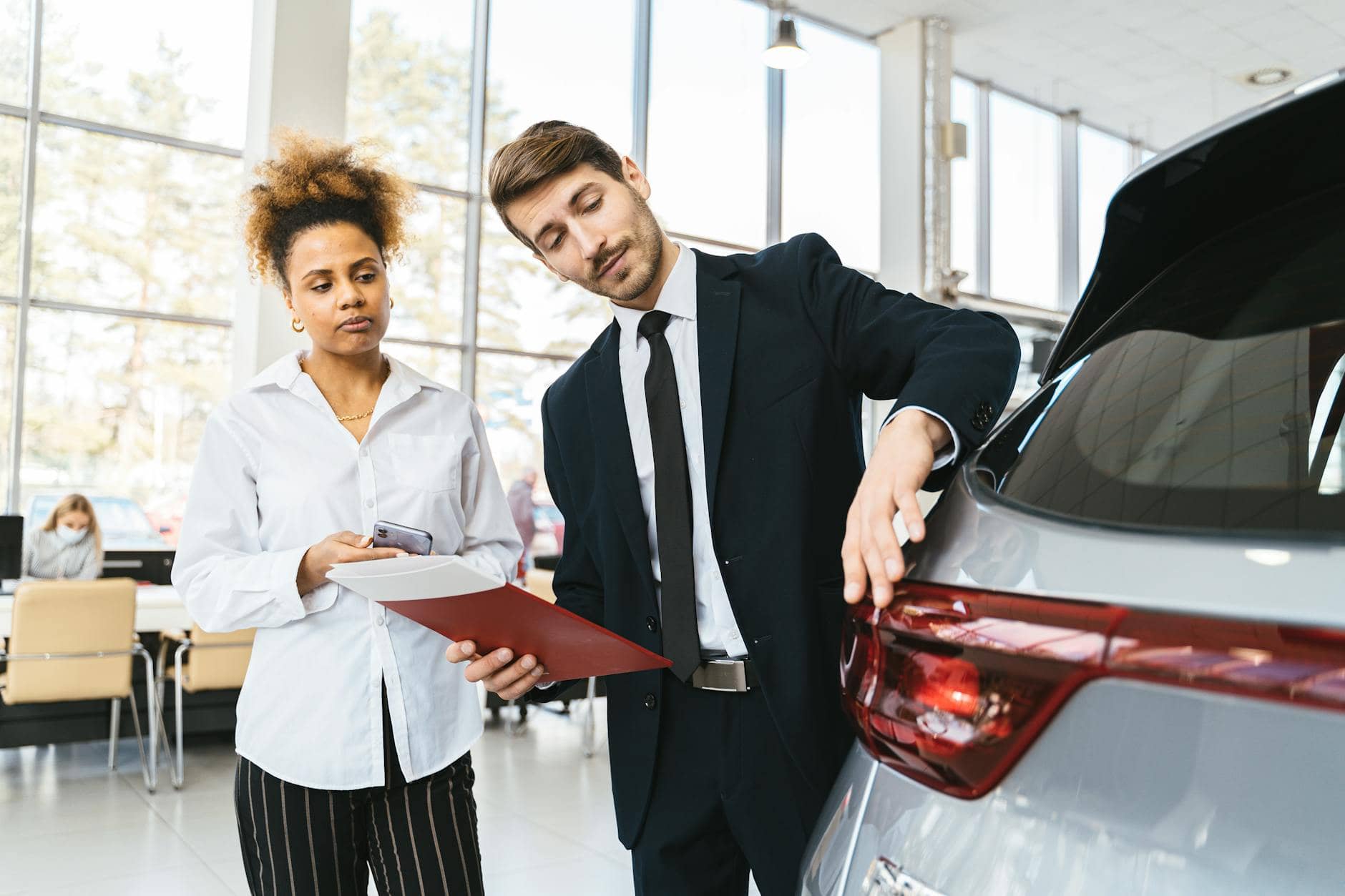 photo of a salesman talking to a customer buying a new car