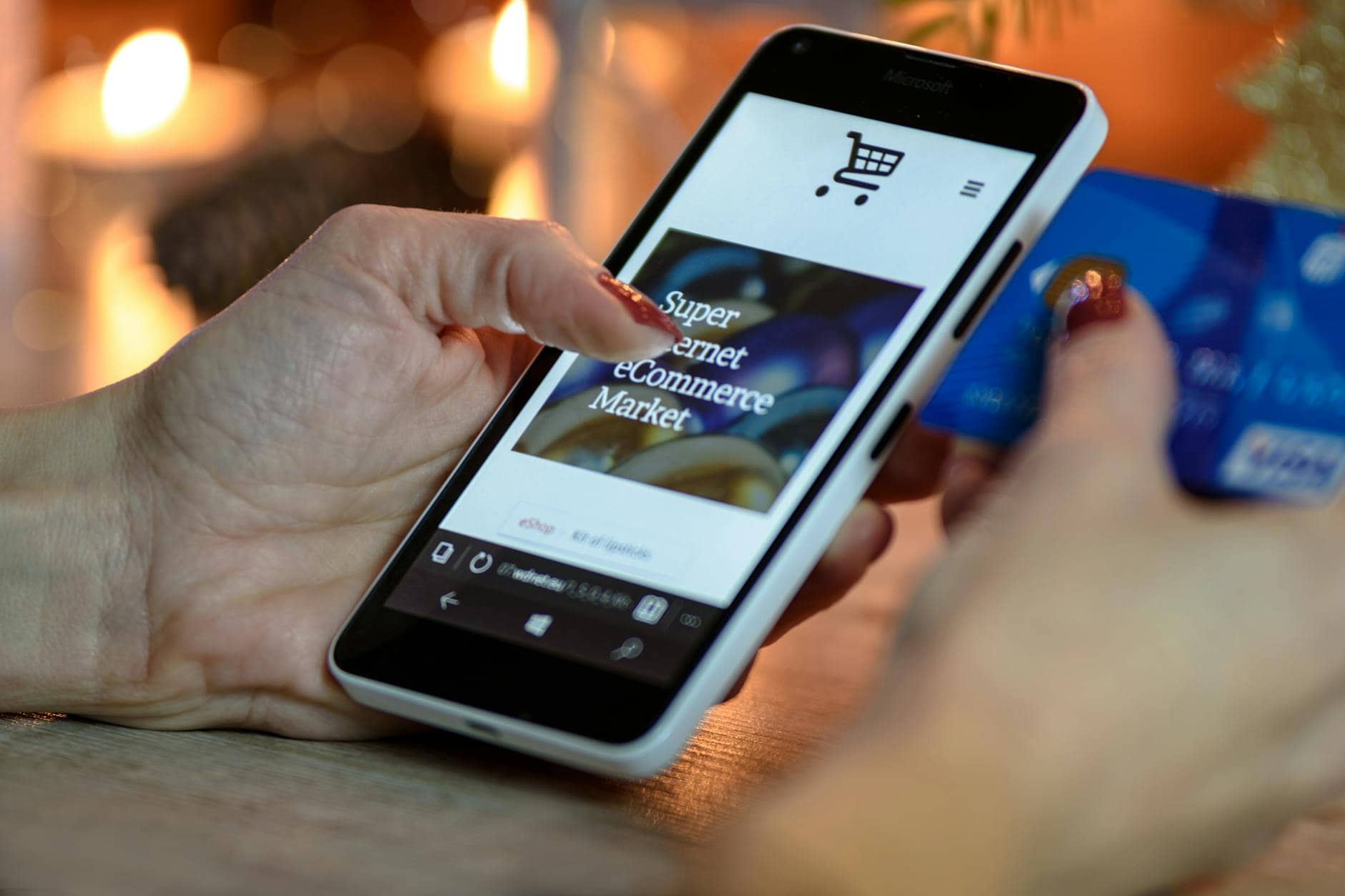 person using black and white smartphone and holding blue card - Running An Ecommerce Business