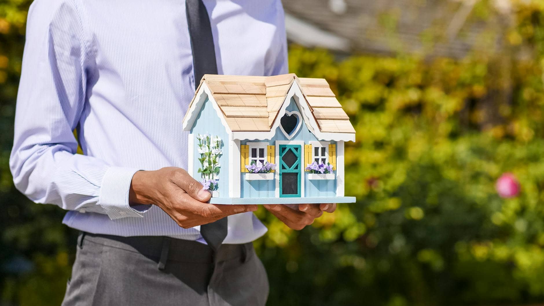 person holding miniature wooden house